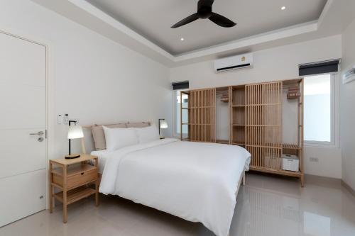 a white bedroom with a large bed and a ceiling fan at Orchid Paradise Homes OPV422 in Hua Hin