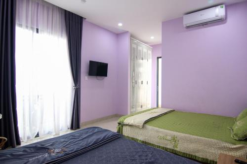 Habitación púrpura con 2 camas y TV. en Nemo Homestay, en Hue