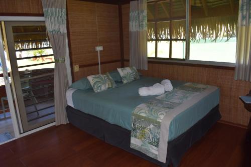 a bedroom with a bed in a room with windows at Fare Aute Beach in Vaianae