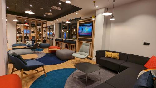 ein Wohnzimmer mit einem Sofa, Stühlen und einem TV in der Unterkunft Holiday Inn Express Bilbao Airport, an IHG Hotel in Derio