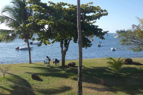 people on the grass near the water with boats at La Mivoie pieds dans l'eau in Rivière Noire
