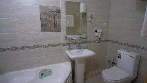 a bathroom with a white toilet and a sink at Xabib&son's hotel in Bukhara