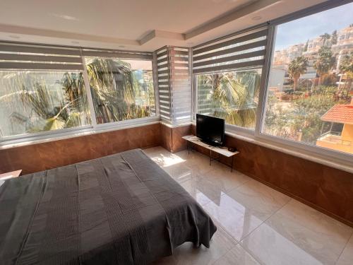 a bedroom with a bed and a tv and large windows at VILLA KONAK CLUB in Alanya