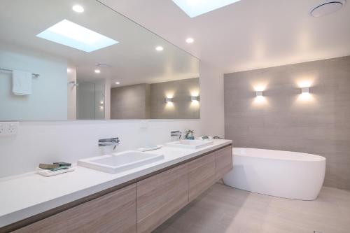 a bathroom with two sinks and a bath tub at Mandalay Luxury Beachfront Apartments in Port Douglas