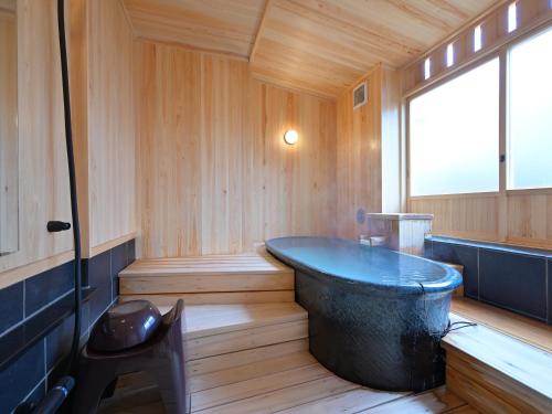 a bath tub in a wooden room with a window at Ryokan Tamura in Kusatsu