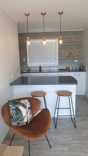 a kitchen with a counter and two stools at Diamond Retreat in Tairua