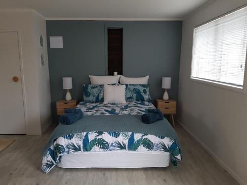 a bedroom with a large bed with blue and white pillows at Diamond Retreat in Tairua