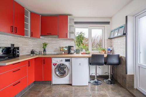 a kitchen with red cabinets and a washing machine at Family Garden Apartments with Free Private Parking & Playground in Rīga