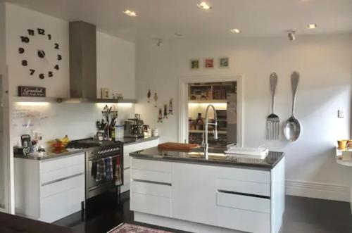 a kitchen with white cabinets and a clock on the wall at Kelburn House at the top of the Cable Car in Wellington