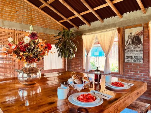 einen Holztisch mit Teller mit Lebensmitteln und Blumen darauf in der Unterkunft Casa monarca in Toluca de Lerdo