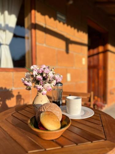 einen Tisch mit einer Schüssel Brot und eine Vase mit Blumen in der Unterkunft Casa monarca in Toluca de Lerdo