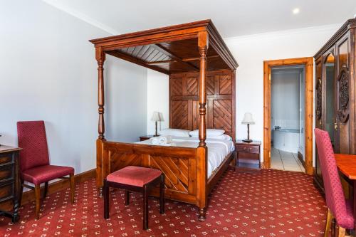 a bedroom with a canopy bed and two red chairs at Columba House in Kingussie