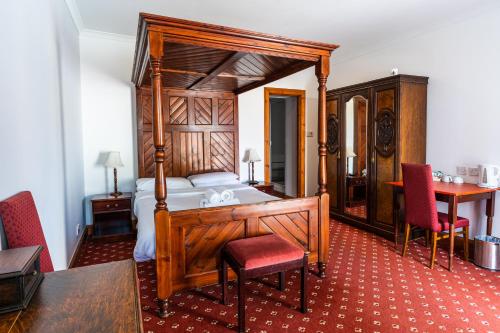 a bedroom with a canopy bed and a table and chairs at Columba House in Kingussie