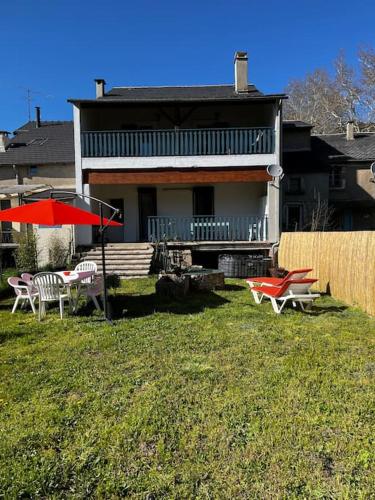 uma casa com um quintal com cadeiras e um guarda-sol em Petit paradis dans l'aveyron em Saint-Jean-du-Bruel