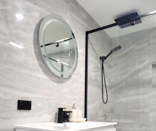 W łazience znajduje się prysznic, lustro i umywalka. w obiekcie Beachside One Bedroom Flat Retreat w mieście Maroochydore