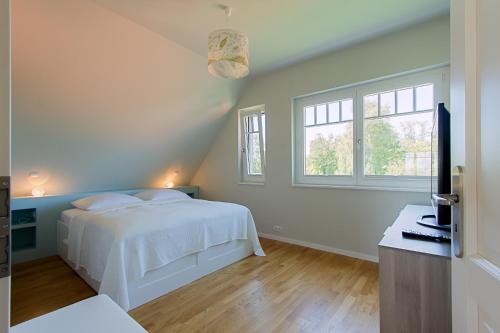 ヴストロにあるHaus am Schilfの白いベッドと2つの窓がある寝室