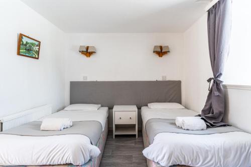 two twin beds in a room with white walls at Columba House in Kingussie