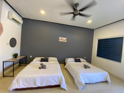 2 bedden in een kamer met een plafondventilator bij Bayu Cenang Inn in Pantai Cenang