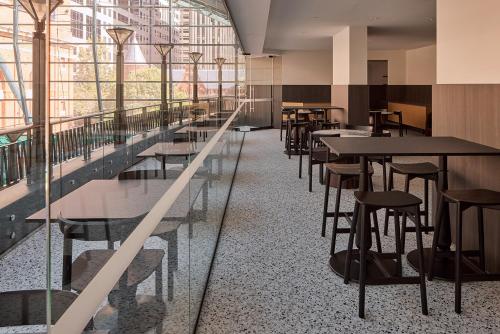 una fila de mesas y sillas en una habitación con ventanas en The Capitol Hotel Sydney en Sídney