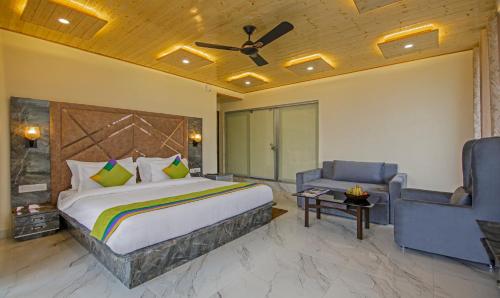 a bedroom with a bed and a couch and a chair at Treebo Ortus Residency in Dharamshala