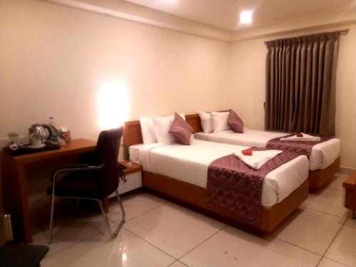 Cette chambre comprend deux lits et un bureau. dans l'établissement Vijay Inn by Unicorn, à Krishnagiri