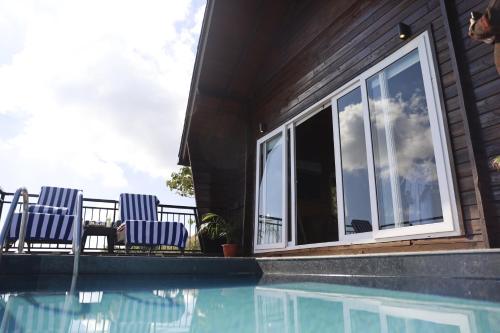 a house with two chairs next to a swimming pool at Polo Cherrapunjee Resort in Cherrapunji