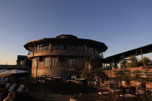 a building with tables and chairs in front of it at Polo Cherrapunjee Resort in Cherrapunji