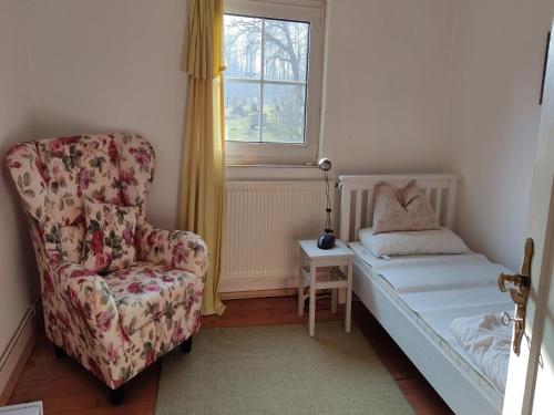 a bedroom with a bed and a chair and a window at Reiterhof Bökensberg in Kasseedorf