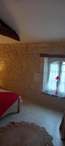 a bedroom with a bed and a window with a flower vase at Gîte Rouge Calme et Nature in Allas-Bocage
