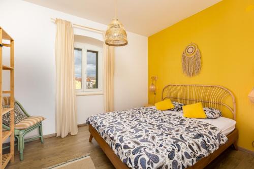 a bedroom with yellow walls and a bed with yellow pillows at In2theRooms Giovanni in Punat
