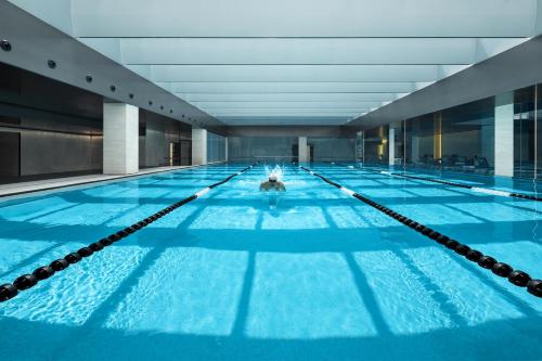 une grande piscine intérieure d'eau bleue dans l'établissement Artisse Place - Access to 4000 sqm Fusion Wellness Centre and 800 sqm Indoor Swimming Pool, à Shenzhen