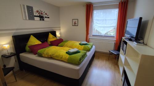 - une chambre dotée d'un lit avec des oreillers jaunes et rouges dans l'établissement Ferienhaus Meier, à Struppen
