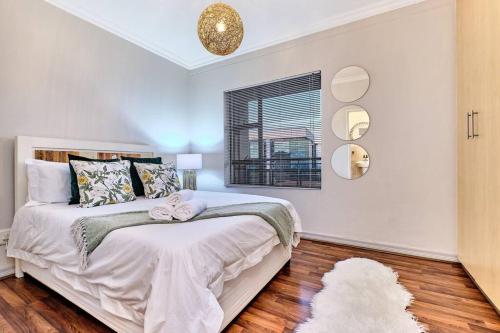 a white bedroom with a bed and a window at Westpoint Executive Suites, Sandton, Johannesburg in Johannesburg