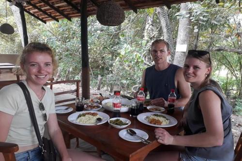 eine Gruppe von Menschen, die an einem Tisch mit Essen sitzen in der Unterkunft Chandi Relax Hostel in Sigiriya