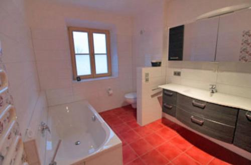 een badkamer met een bad, een wastafel en een toilet bij Fewo B33 in Übersee