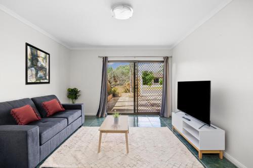 a living room with a couch and a tv at Swainson on Margaret in Oaklands