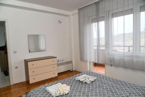 a bedroom with a bed and a dresser and a window at ASPERA Apartments in Kumanovo