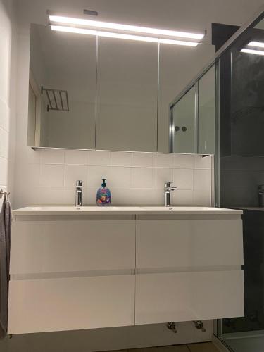 a white bathroom with a sink and a mirror at WeLoveOostende - Newly renovated large apartment 150m from the beach - Including bed sheets and final clea-ning in Ostend