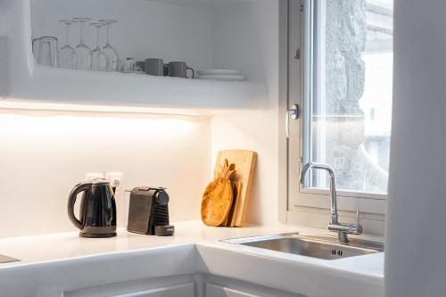 a kitchen counter with a sink and a window at Koumi Homes Mykonos in Ftelia