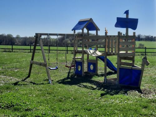un parque infantil con dos columpios en un campo en Au Temps Retrouvé en Nouans-les-Fontaines