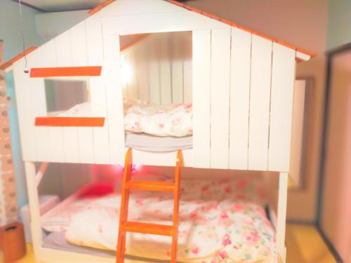 ein Puppenhaus mit einem Bett und einem Stuhl in der Unterkunft ゲストハウス　アンブレラ in Soma