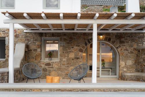 a patio with two chairs and a stone wall at Koumi Homes Mykonos in Elia