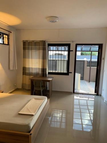 a bedroom with a bed and a table and windows at Residence La Colombe in Grand Baie
