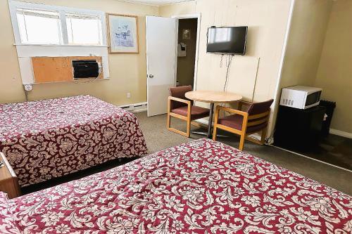 a hotel room with two beds and a table and a television at Love Hotels Timberline at Lake Superior MI in Ironwood