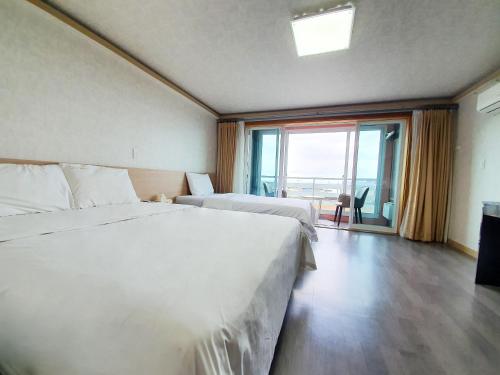 a hotel room with two beds and a large window at Jeju Ocean Family Hotel in Jeju