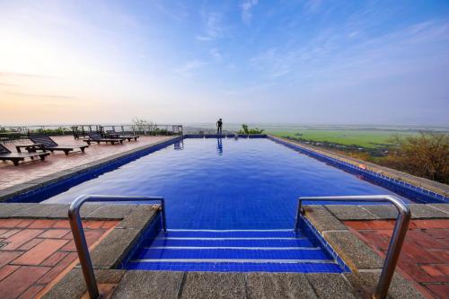 a swimming pool with blue water and benches at Victoria Nui Sam Lodge in Chau Doc