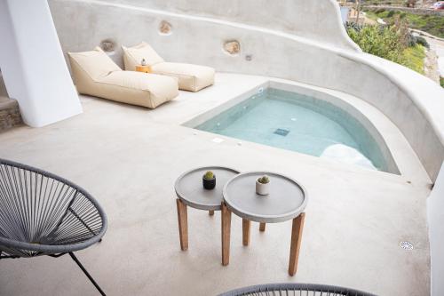 a patio with a swimming pool with two tables and chairs at Koumi Homes Mykonos in Elia