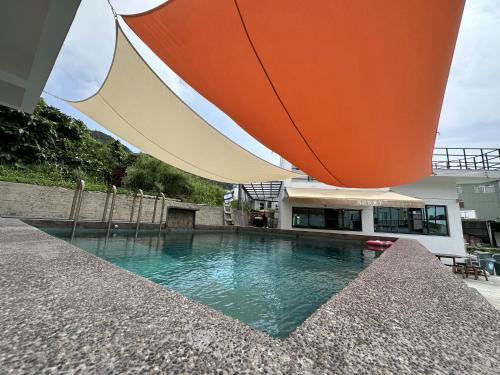 a swimming pool in front of a building with an umbrella at Oceans Explore Hostel in Green Island