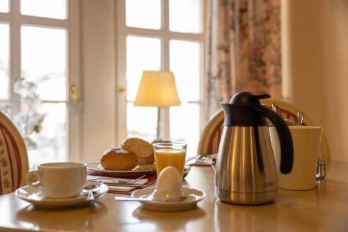 a table with a coffee pot and a cup of orange juice at Hotel Anker in Saalfeld