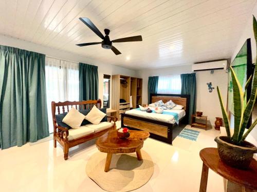 a living room with a bed and a ceiling fan at Le Port Guest House in Baie Sainte Anne